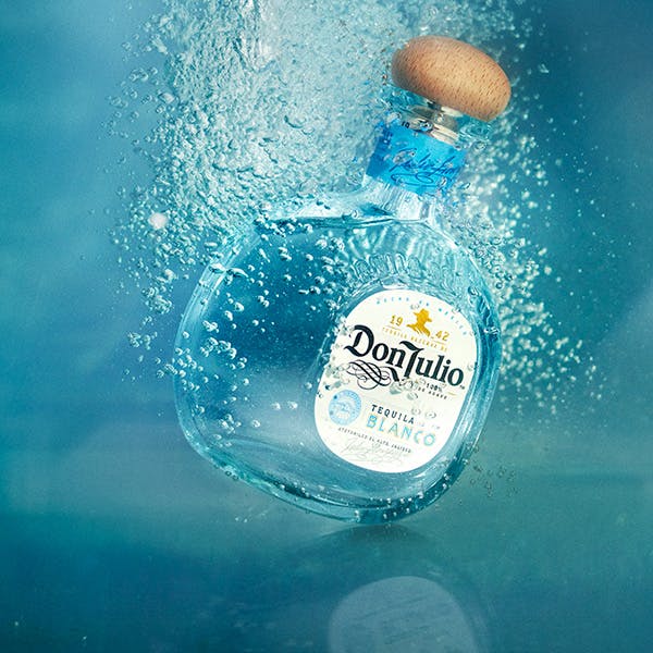 a bottle of Don Julio Blanco submerged in water with bubbles rising from it