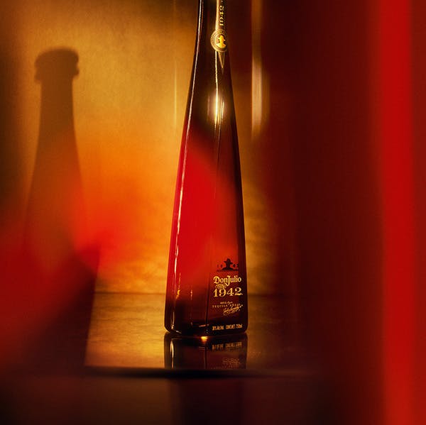 A bottle of Don Julio 1942 on a surface with a red and golden background